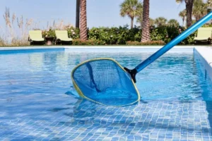 Blue pool net submerged in clear turquoise water during daytime, used for professional pool cleaning.